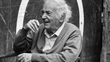 Imagem mostra um idoso rindo com seus amigo em uma mesa