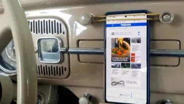 Imagem mostra o painel de um fusca com um celular sendo segurado por um elástico