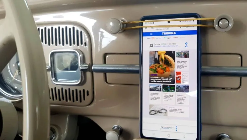 Imagem mostra o painel de um fusca com um celular sendo segurado por um elástico