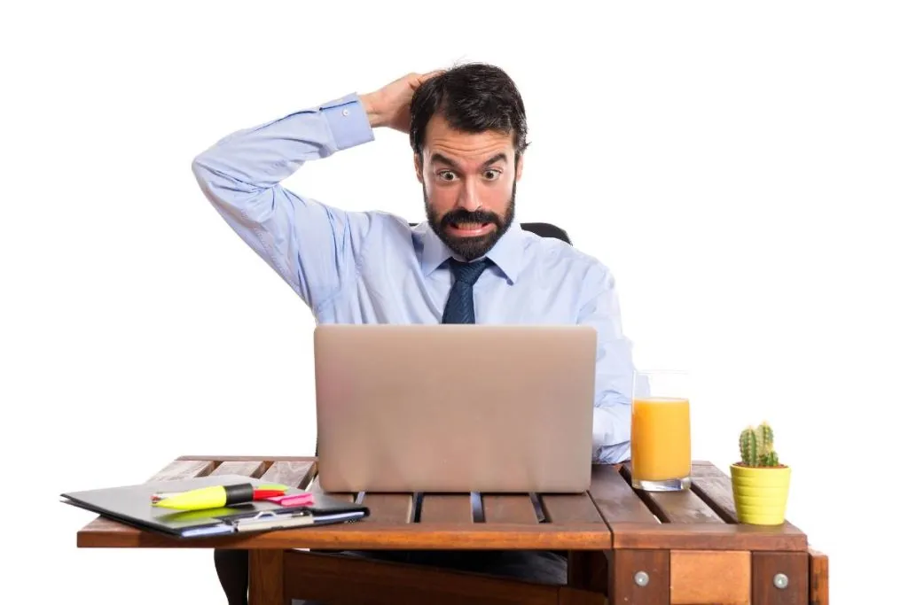 Imagem mostra um homem desesperado na frente de um computador.