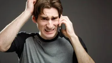 Imagem mostra um homem nervoso ao celular.