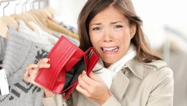 Imagem mostra uma mulher com cara de desespero abrindo uma carteira vazia, sem dinheiro.