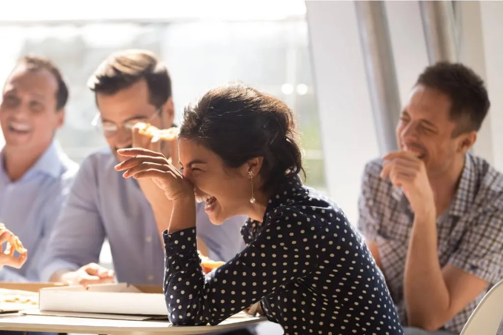 Imagem mostra pessoas rindo no trabalho.