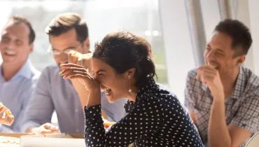 Imagem mostra pessoas rindo no trabalho.