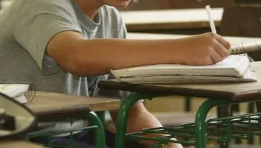 Imagem mostra um estudante em uma sala de aula.