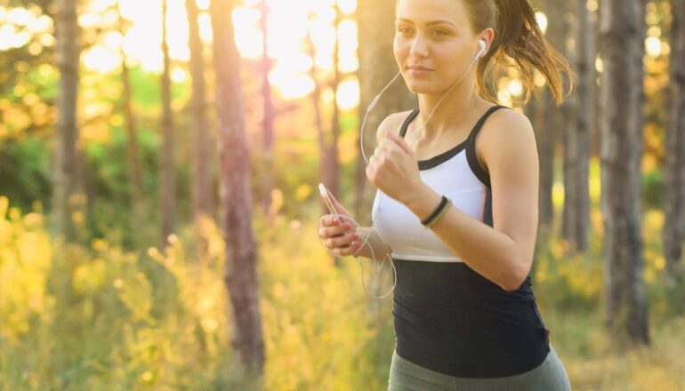 Mulher com roupa de academia corre em uma floresta