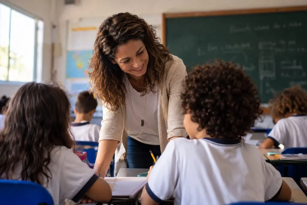 Professora falando com dois alunos em sala de aula