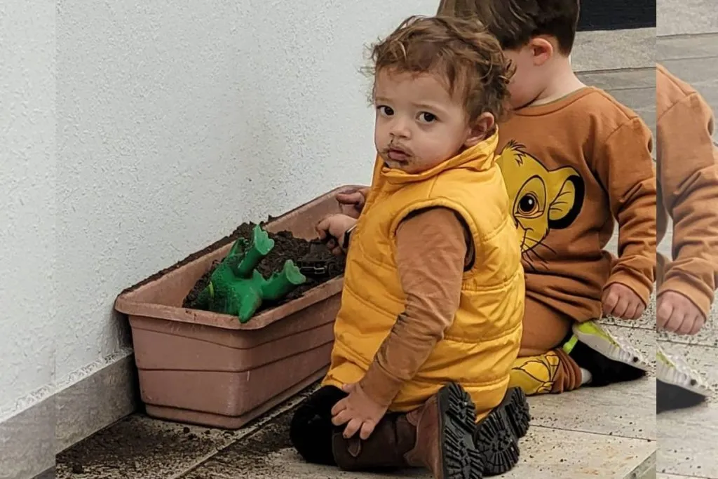 Imagem mostra um bebê de 2 anos brincando na terra.