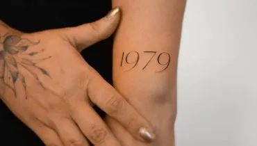 Imagem mostra uma tatuagem escrito 1979 no braço de uma mulher.